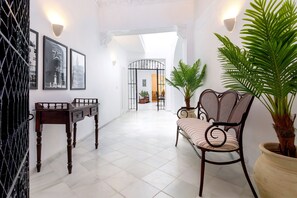 A hallway with a wooden table, a wicker chair, and a potted plant. - Genteel Home Patio del Arenal 201 (Seville)