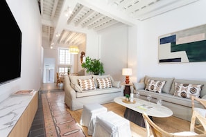 A spacious living room with a high ceiling, a sofa set, a coffee table, and a television mounted on the wall. - Genteel Home Patio del Arenal 201 (Seville)