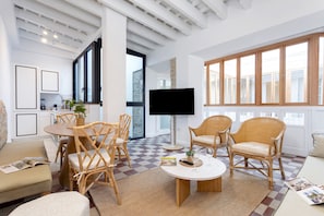 A modern living room with a dining area, large windows, and a flat-screen TV. - Genteel Home Patio del Arenal Terrace 301 (Seville)