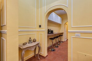 A corridor with a bar area, a decorative table, and a seating arrangement. - Sunflower Suite by MMega (Firenze)