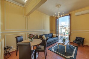 A living room with a sofa, chairs, a table, and a chandelier. - Sunflower Suite by MMega (Firenze)