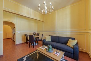A living room with a sofa, coffee table, and a chandelier. - Sunflower Suite by MMega (Firenze)