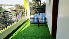 A balcony with artificial grass, a metal railing, and a blue-striped chair. - GRANADA HOTEL NAIROBI  (Westlands)