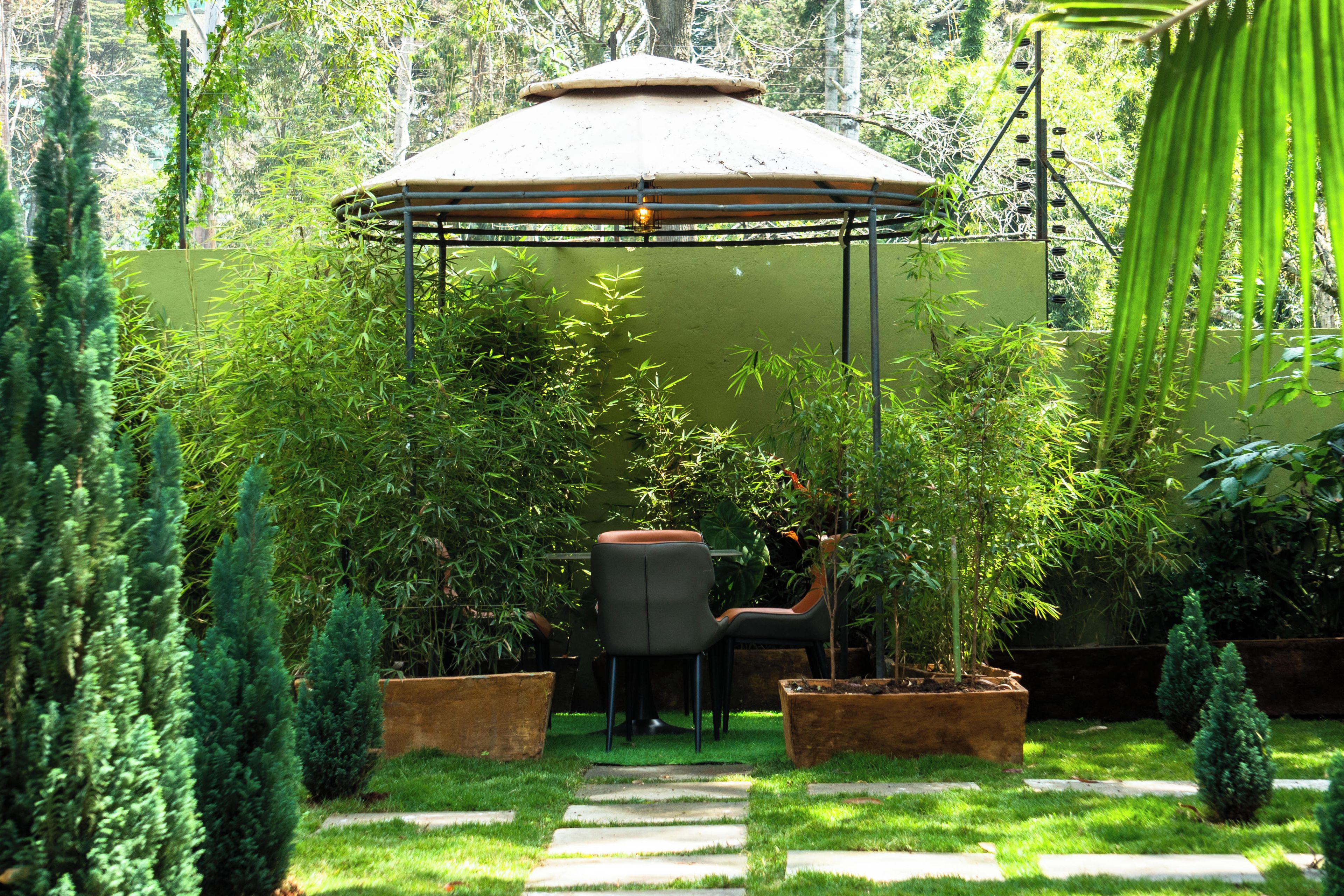 Un jardín con un pabellón, una silla y plantas en macetas.