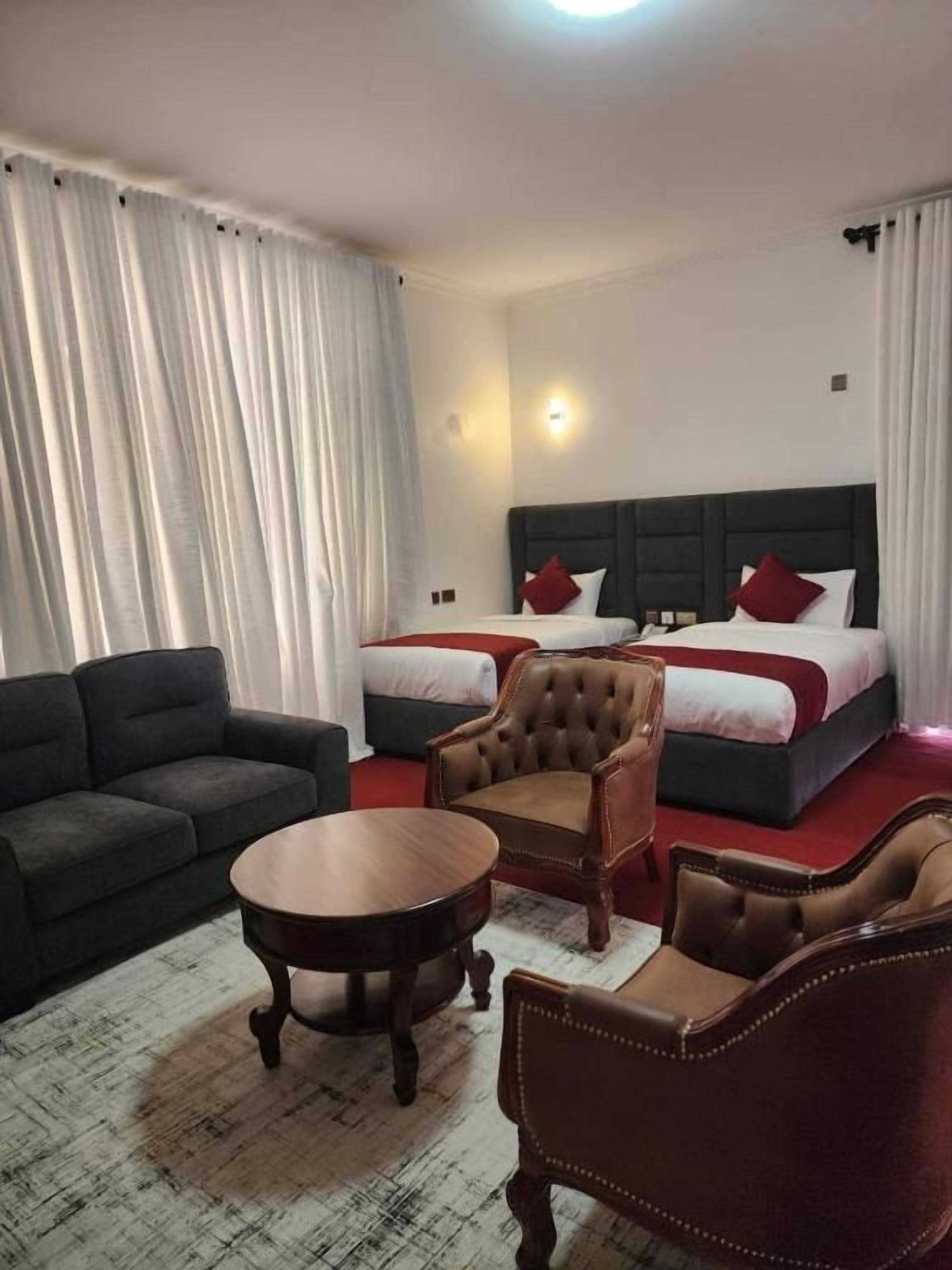 Una habitación de hotel con una cama, dos sofás, una mesa de centro redonda y una silla.