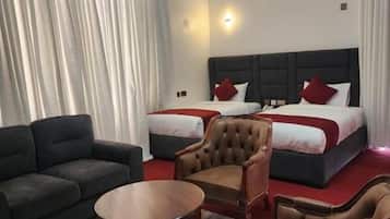 Una habitación de hotel con una cama, dos sofás, una mesa de centro redonda y una silla.