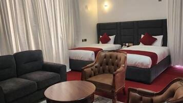 A hotel room with two beds, a sofa, a chair, and a small table.