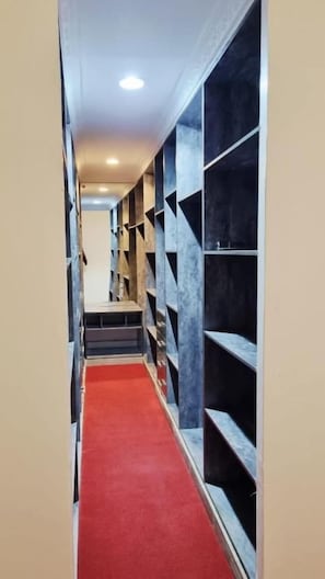 A narrow hallway with a red carpet, flanked by shelves on both sides. - GRANADA HOTEL NAIROBI  (Westlands)