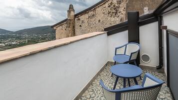 Ein Balkon mit Blick auf eine Stadt und Berge, mit einem Tisch und zwei Stühlen.
