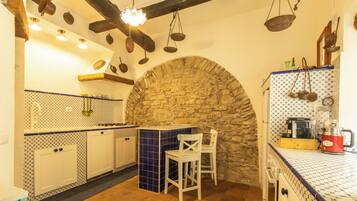 A kitchen with stone arch, white cabinets, and hanging utensils.