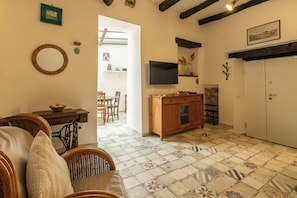 A living room with a sofa, a wooden cabinet, a television, and a patterned floor. - Borgo 1660 - Dimora di Charme (Castellabate)