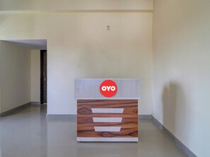 Un mostrador de recepción con un logotipo, un diseño de panel de madera y un suelo de color claro.