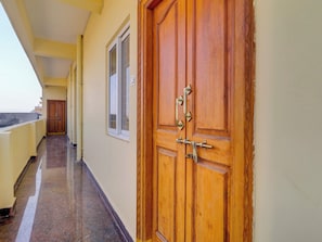 Un passadís amb una porta de fusta, una finestra i un balcó.