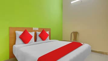 Una habitación de hotel con una cama, una mesita de noche, una silla y una lámpara fijada a la pared.
