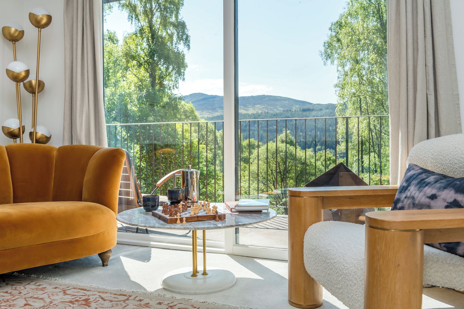 Ein modernes Wohnzimmer mit Sofa, Sessel und Couchtisch, mit Schachbrett und Kaffeekanne.