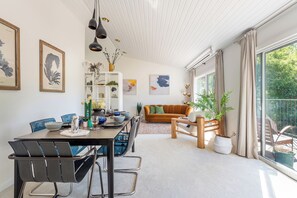 A dining area with a table set for four, a sofa, and a large window with curtains. - Secluded house on 12 acres, set in the tree canopy, loch views and private beach (Strathtumel)