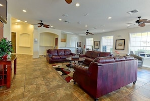 A spacious living room with leather sofas, a coffee table, and ceiling fans. - Roomy 3-Bed/2.5-Bath Townhome - Disney (Kissimmee)
