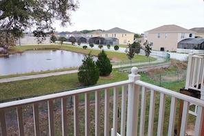 A residential area with a pond, a walking path, and houses with a uniform architectural style. - Roomy 3-Bed/2.5-Bath Townhome - Disney (Kissimmee)