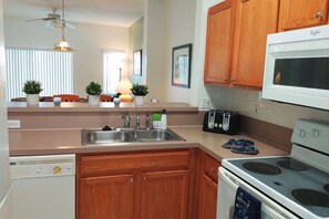 A kitchen with wooden cabinets, a double sink, a stove, and a microwave. - Roomy 3-Bed/2.5-Bath Townhome - Disney (Kissimmee)