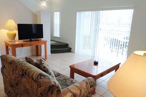 A living room with a television, a sofa, a coffee table, and a lamp. - Roomy 3-Bed/2.5-Bath Townhome - Disney (Kissimmee)