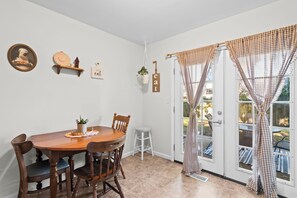 A dining area with a wooden table and chairs, a hanging plant, and a wall-mounted sign. - Lynnhaven Landing – Cozy Springfield Getaway (Springfield)