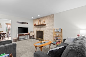 A living room with a fireplace, a television, a bookshelf, and a sofa. - Lynnhaven Landing – Cozy Springfield Getaway (Springfield)