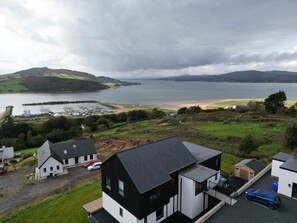 Une propriété située sur la côte, comprenant une maison moderne, un port de plaisance et une plage.