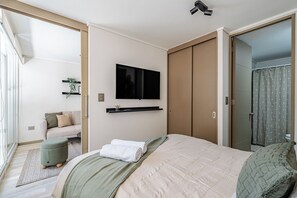 A modern bedroom with a bed, a TV mounted on the wall, and a sliding door closet. - Charming 1BR in Santiago WiFi (Santiago)