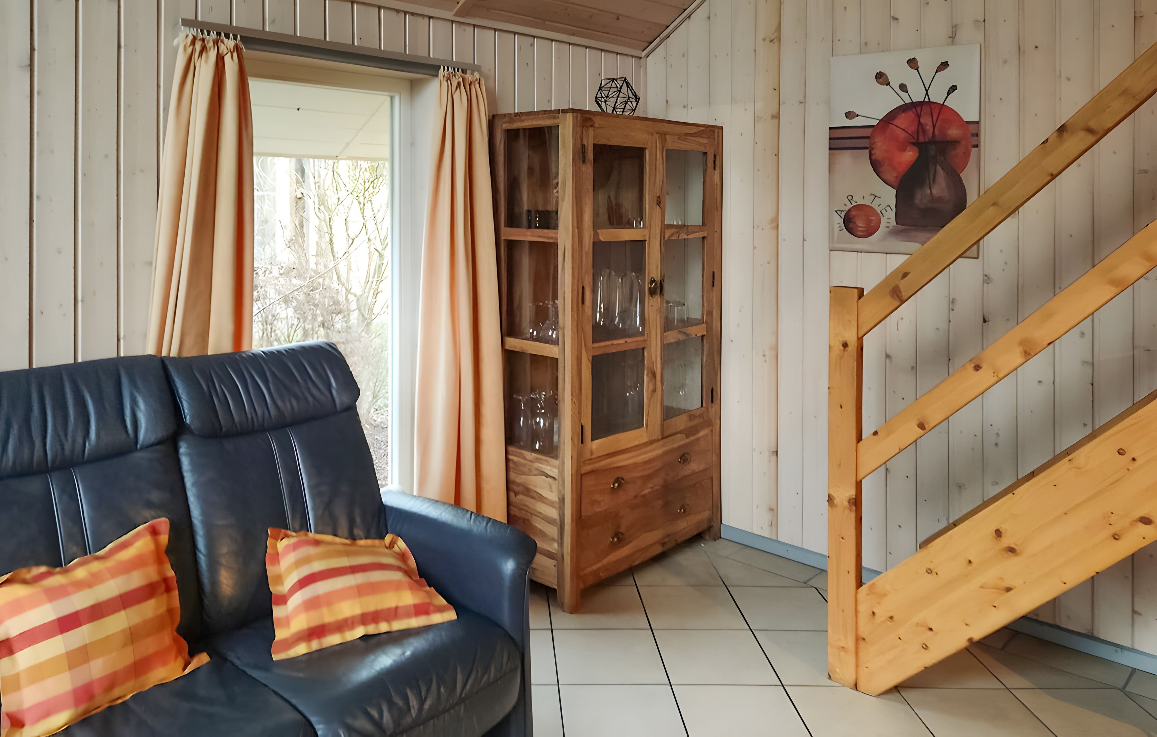 Ein Wohnzimmer mit einer Ledersofa, einem Holzkabinett und einer Treppe.