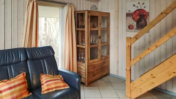 Een woonkamer met een leren bank, een houten kast en een trap.