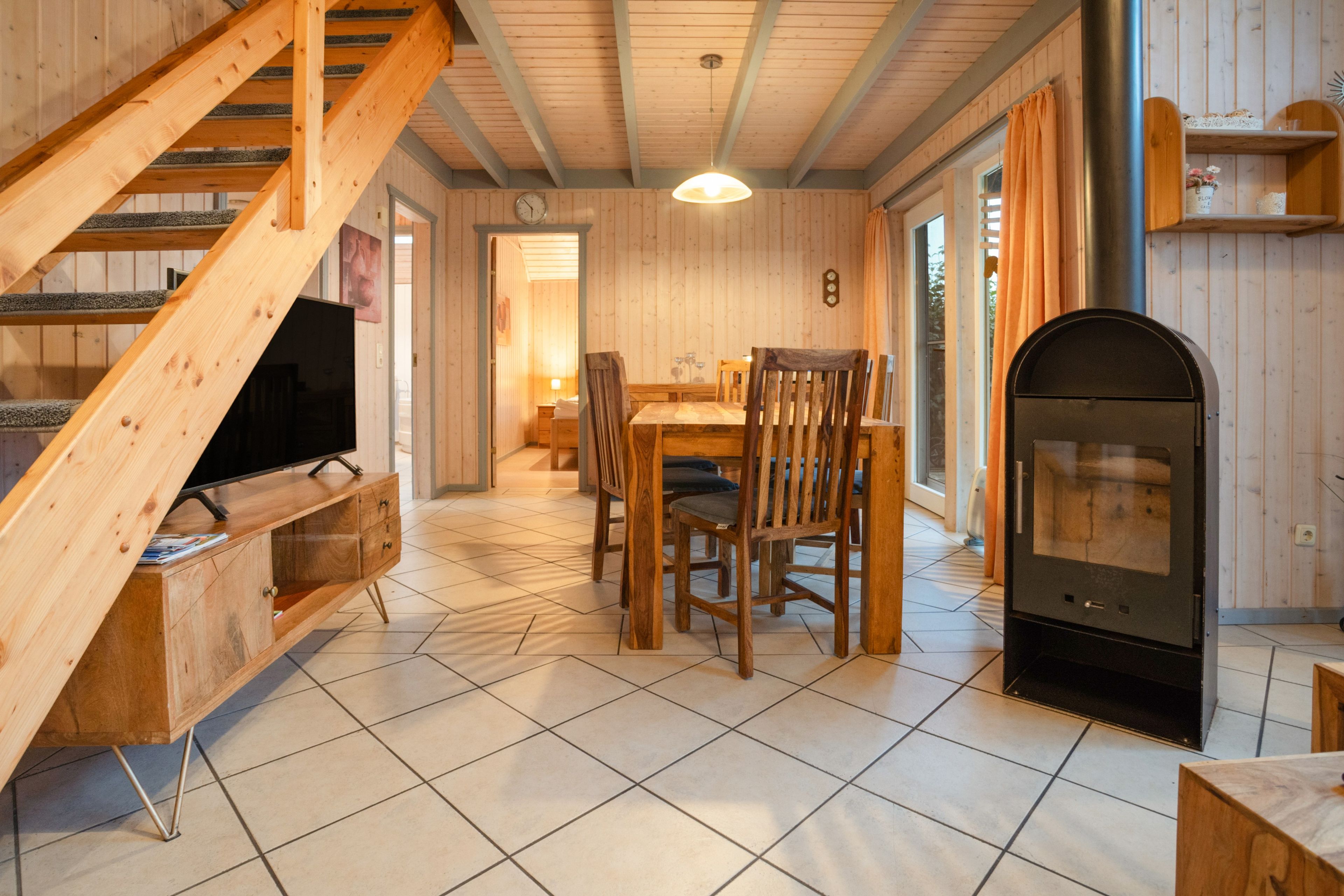 Een houten interieur met een trap, een eethoek en een open haard.