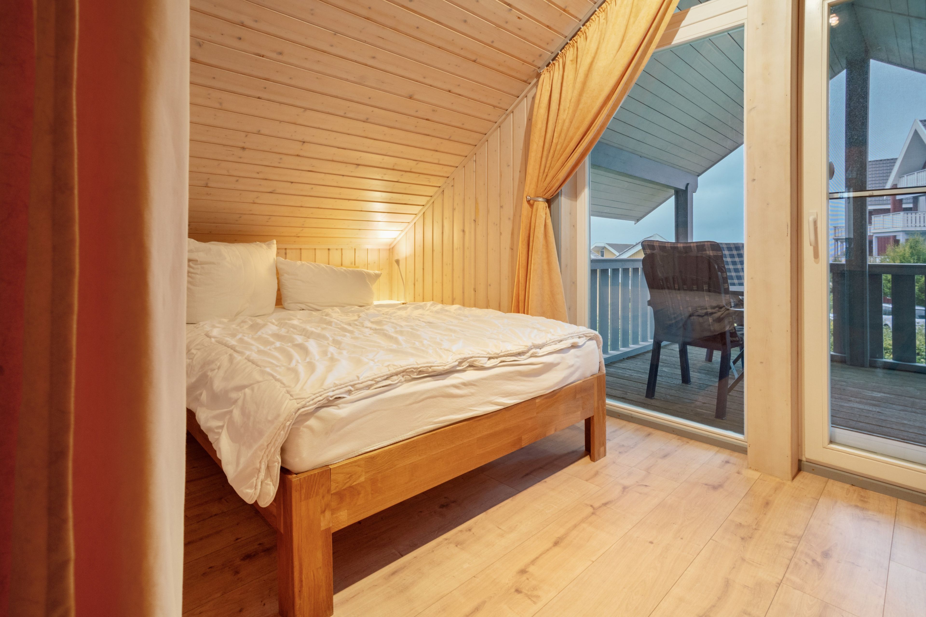 Ein hölzernes Bett in einem Zimmer mit einem Balkon.