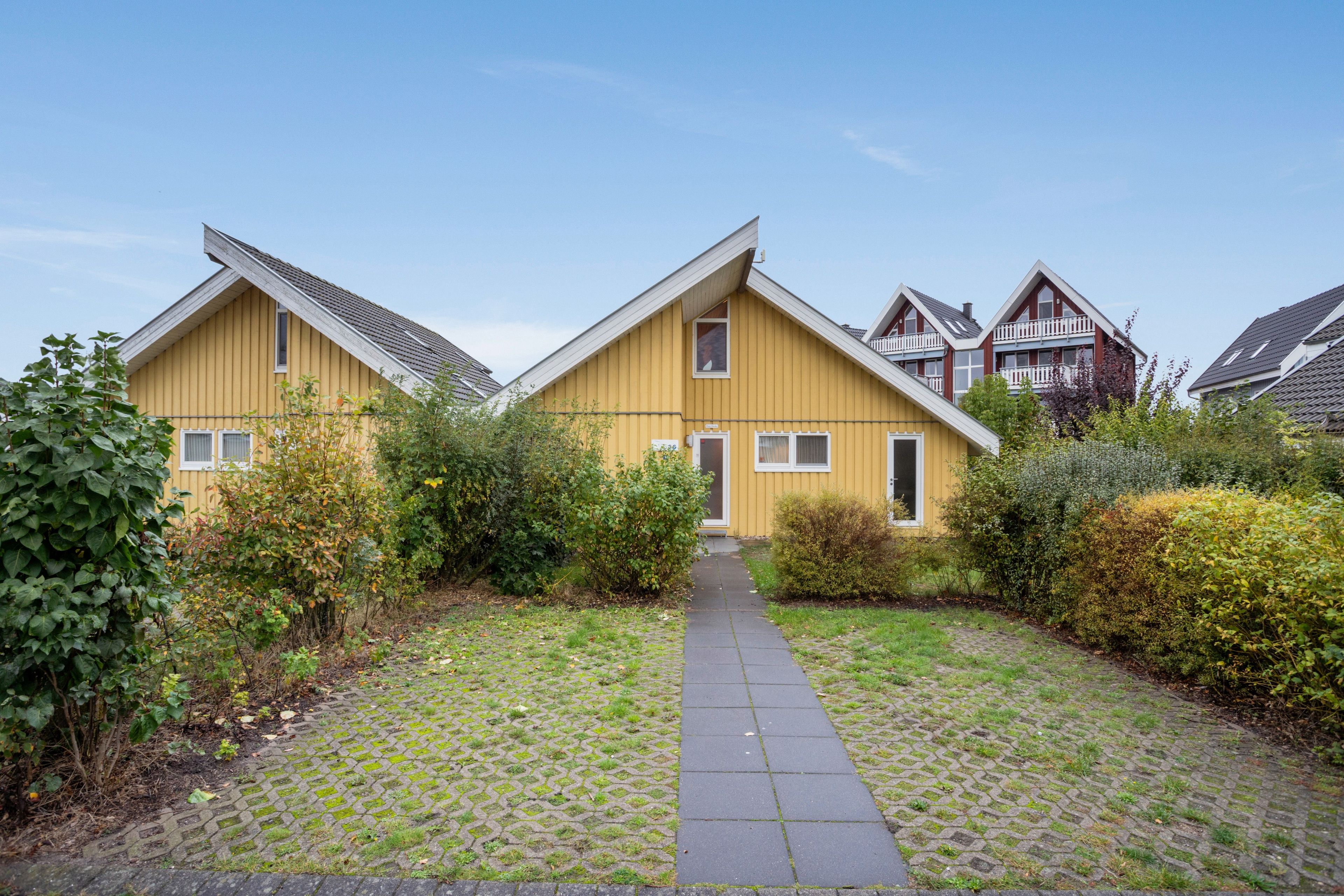 Une rangée de maisons jaunes, avec un chemin pavé menant à l’entrée.