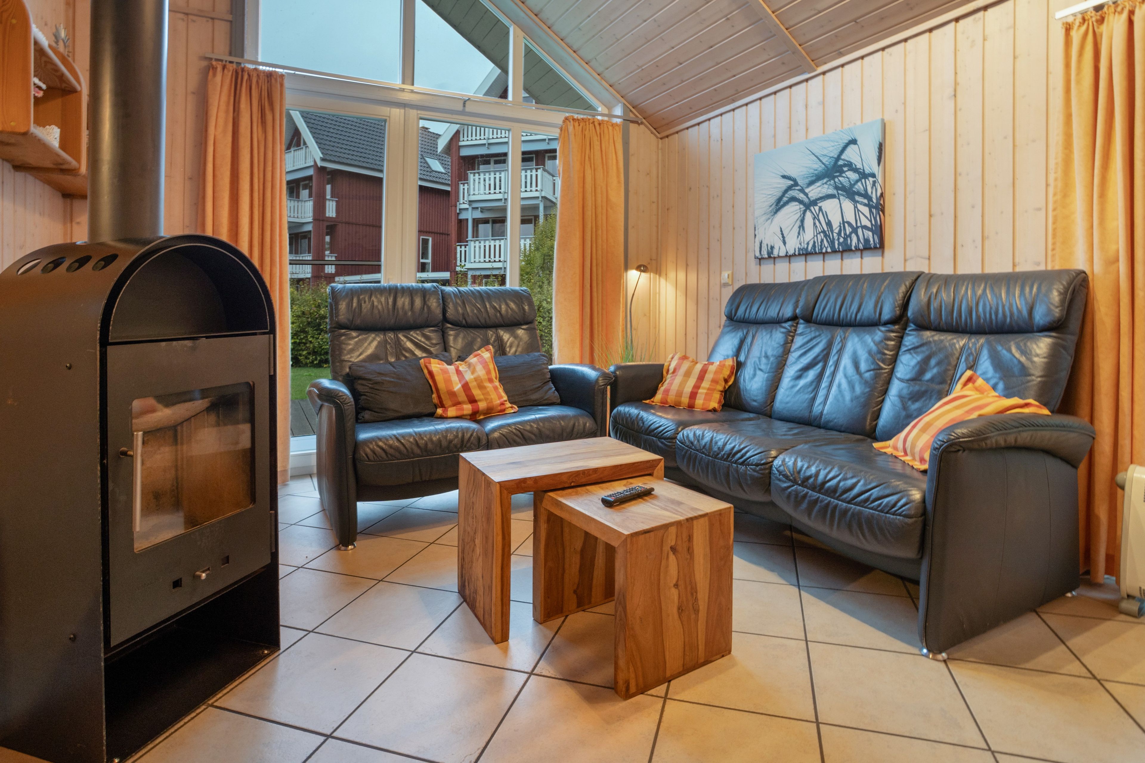 Un salon avec une cheminée, deux canapés, une table basse et une vue sur un immeuble d’habitation.