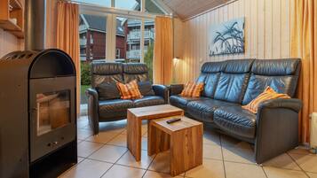 Un salon avec une cheminée, deux canapés, une table basse et une vue sur un immeuble d’habitation.