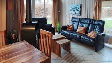 Una sala de estar acogedora con una mesa de madera, un sofá de cuero negro con cojines a rayas y un cuadro en la pared.