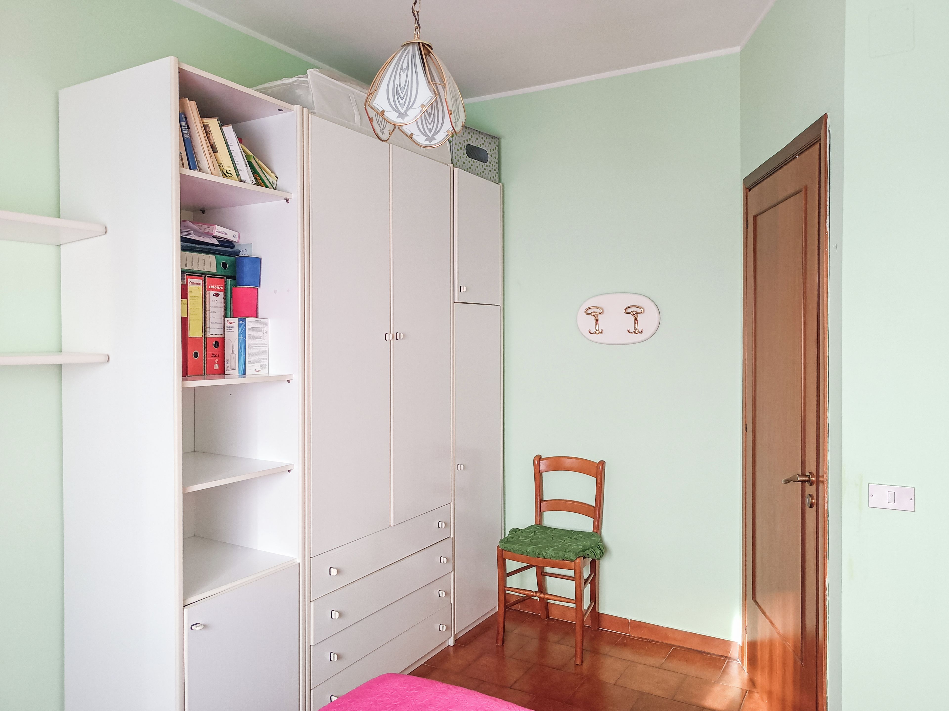 Una habitación con armario, una silla, una puerta y una lámpara.