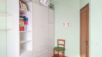 Una habitación con armario, una silla, una puerta y una lámpara.