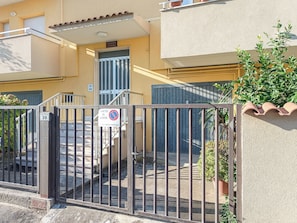 Una entrada tancada a un edifici, amb un senyal que indica zona prohibida per aparcar i una escala que mena a un nivell superior.