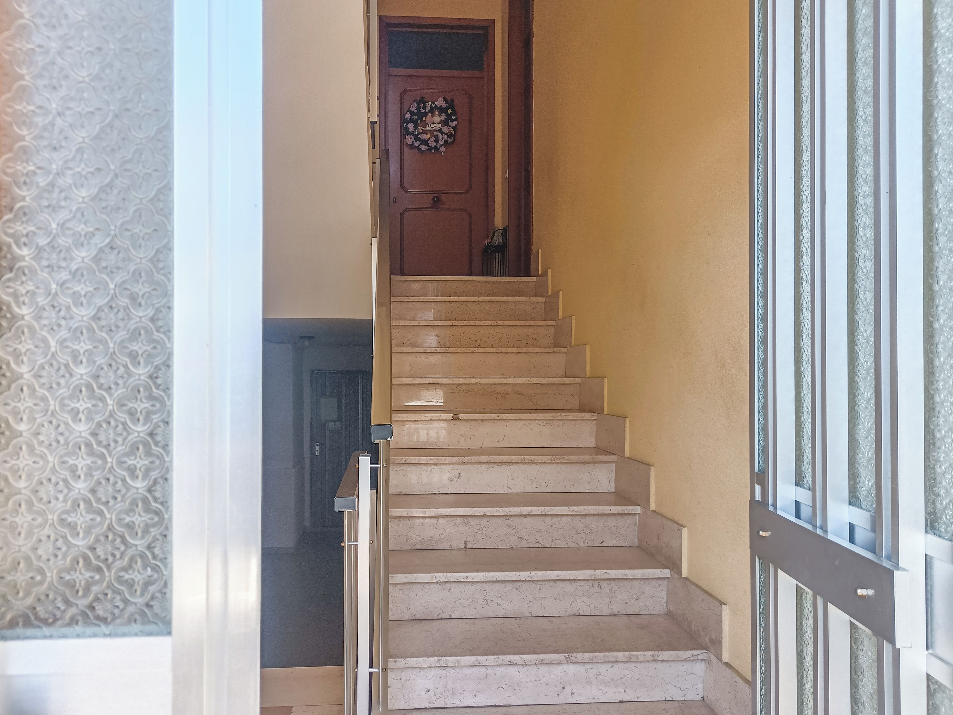 A staircase with a wooden door at the top and a patterned wall on the left.