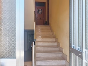 Una escala amb una porta de fusta a dalt i una paret amb dibuixos al costat esquerre.