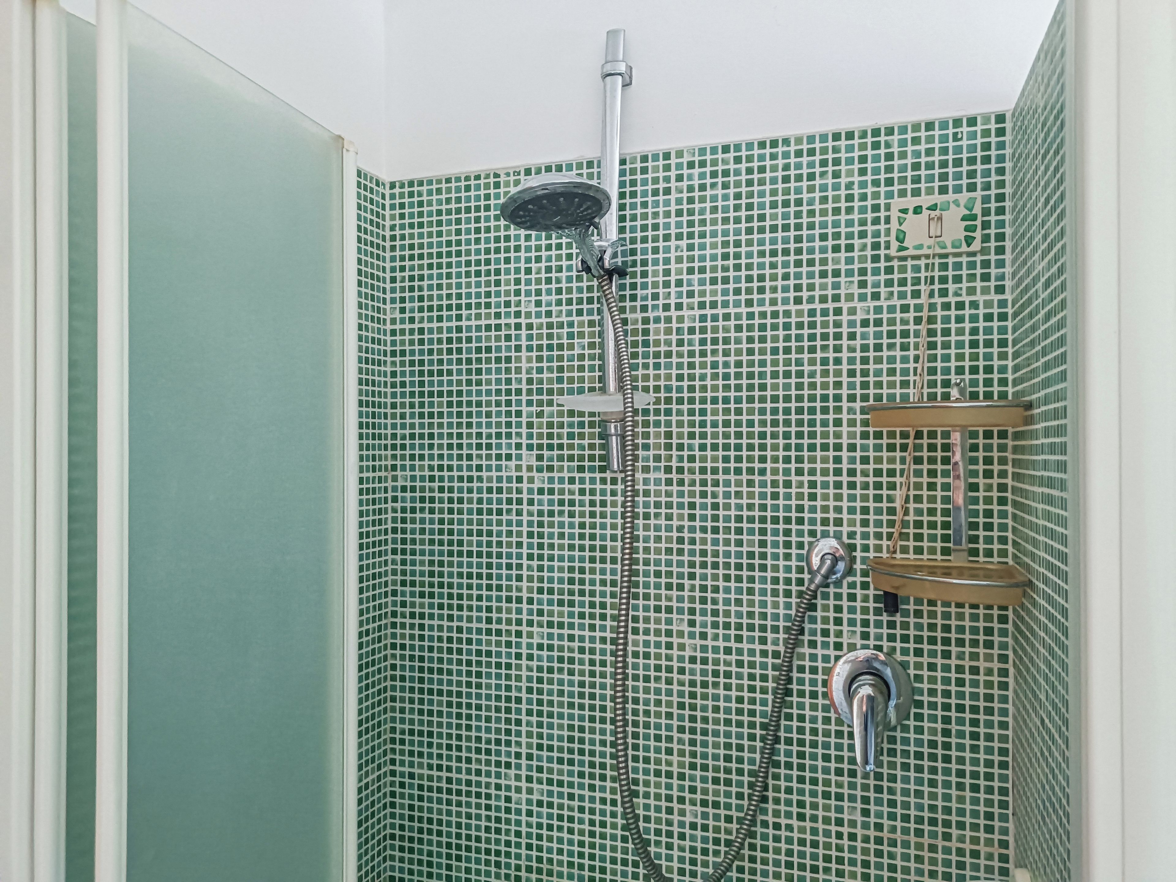 Eine Dusche mit Duschbrause und Wandarmatur.