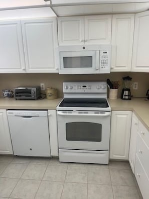 A kitchen with white cabinets, a microwave, a toaster, a coffee maker, and a dishwasher. - Old Naples Boater's Retreat Oyster Bay Boat 27 ft. slip to rent (Naples)