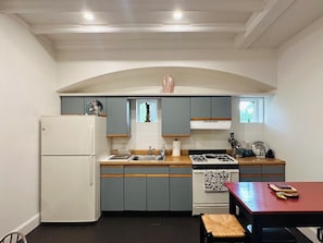 A kitchen with a white refrigerator, a stove, and a sink. There is a window above the sink and a decorative item on the wall. - “2-bedroom apartment in a historic carriage house with garden” (Lambertville)