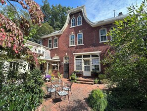 A two-story brick house with a covered patio area. - “2-bedroom apartment in a historic carriage house with garden” (Lambertville)