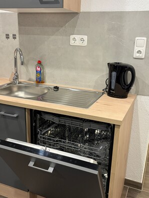 Eine Küche mit Geschirrspüler, Kaffeemaschine und einer Flasche Spülmittel.