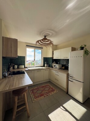 A modern kitchen with a central island, white cabinetry, a built-in microwave, and a refrigerator.