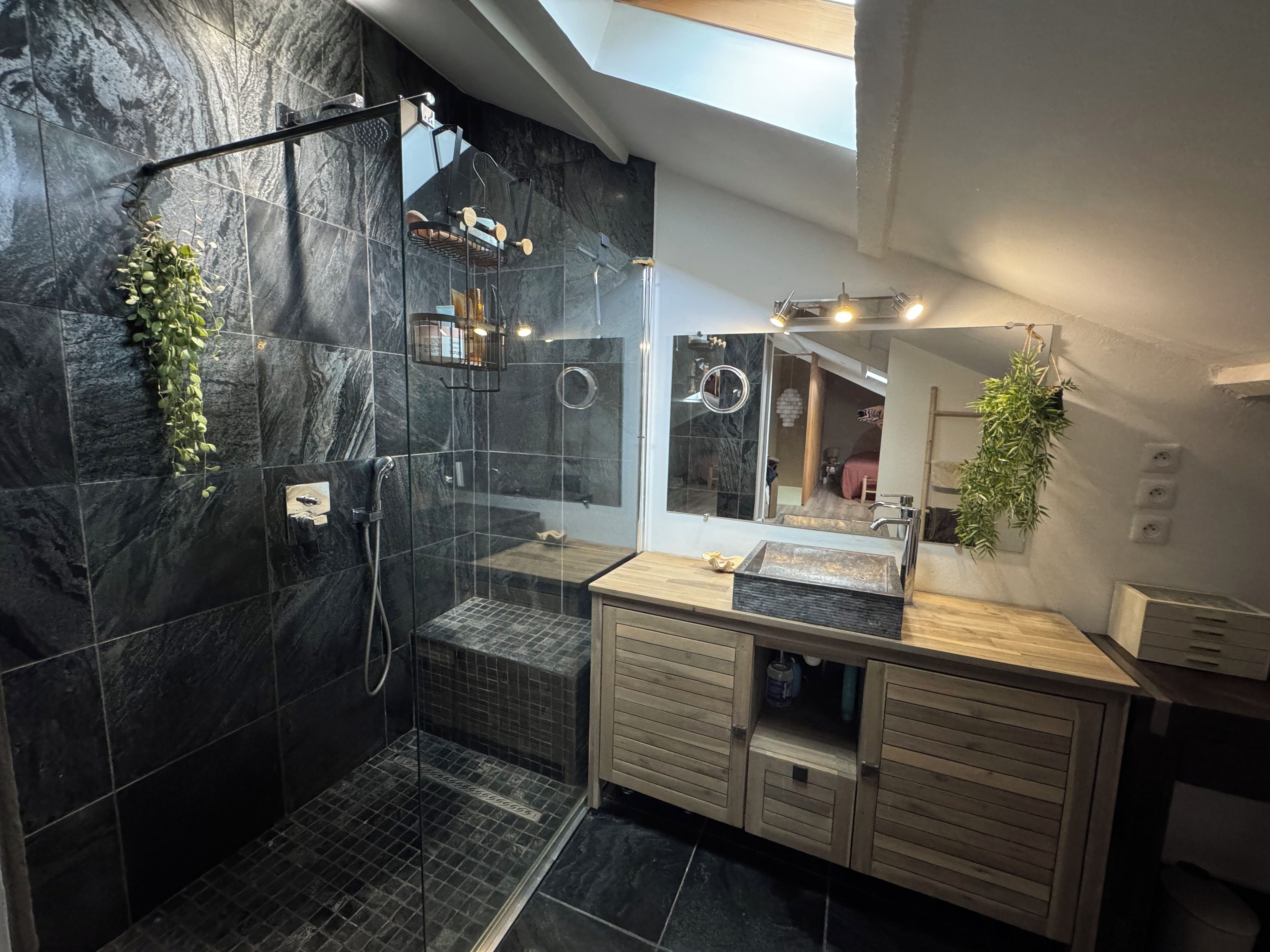 Une salle de bain moderne avec une douche à parois de verre, un meuble-lavabo en bois et un grand miroir.