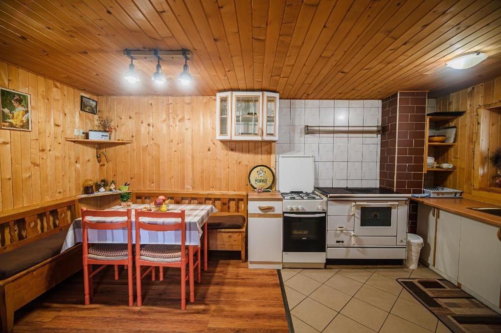 Um interior de madeira com uma mesa de jantar, cadeiras, um fogão e uma geladeira.