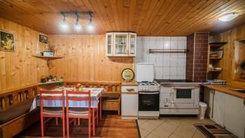 Um interior de madeira com uma mesa de jantar, cadeiras, um fogão e uma geladeira.